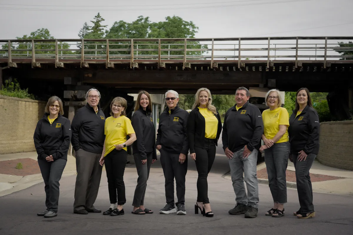 The Bridge Realty southern Minnesota agents standing together beneath the Sibley Park pedestrian bridge in Mankato